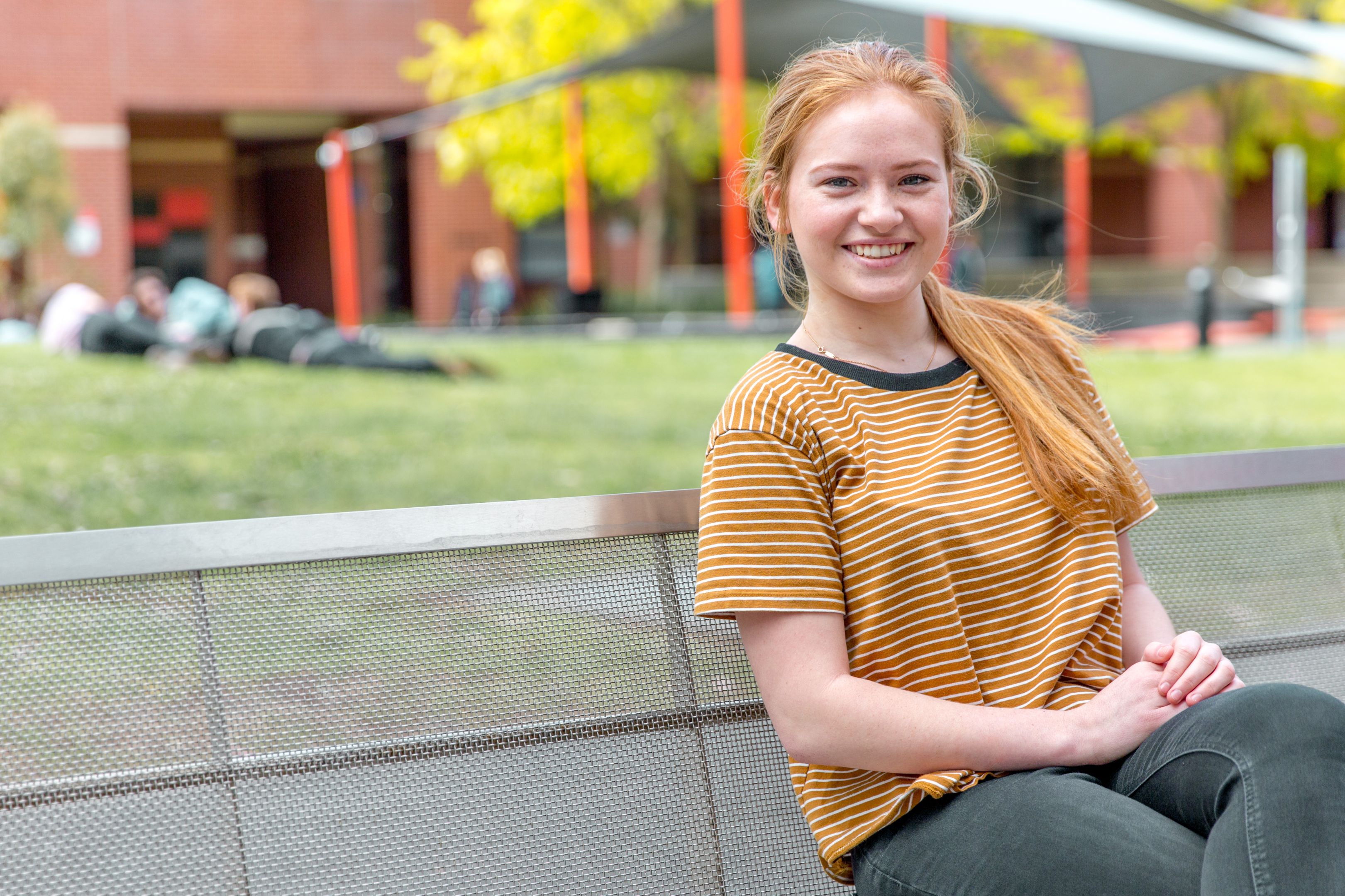 Young woman sits on bench smiling at camera