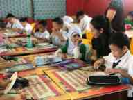 Students sitting at their desks while a Swinburne preservice teacher looks on in a classroom in Malaysia