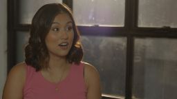 Brunette woman wearing a pink top with a shocked expression on her face