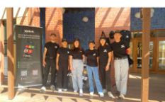 Group of people standing together, smiling for the camera outside.
