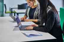 Students studying online at a desk on their laptops