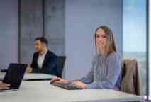 A young professional woman sitting at a keyboard during a business meeting.