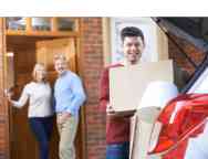 Young male moving out of home, moving boxes into his silver car 