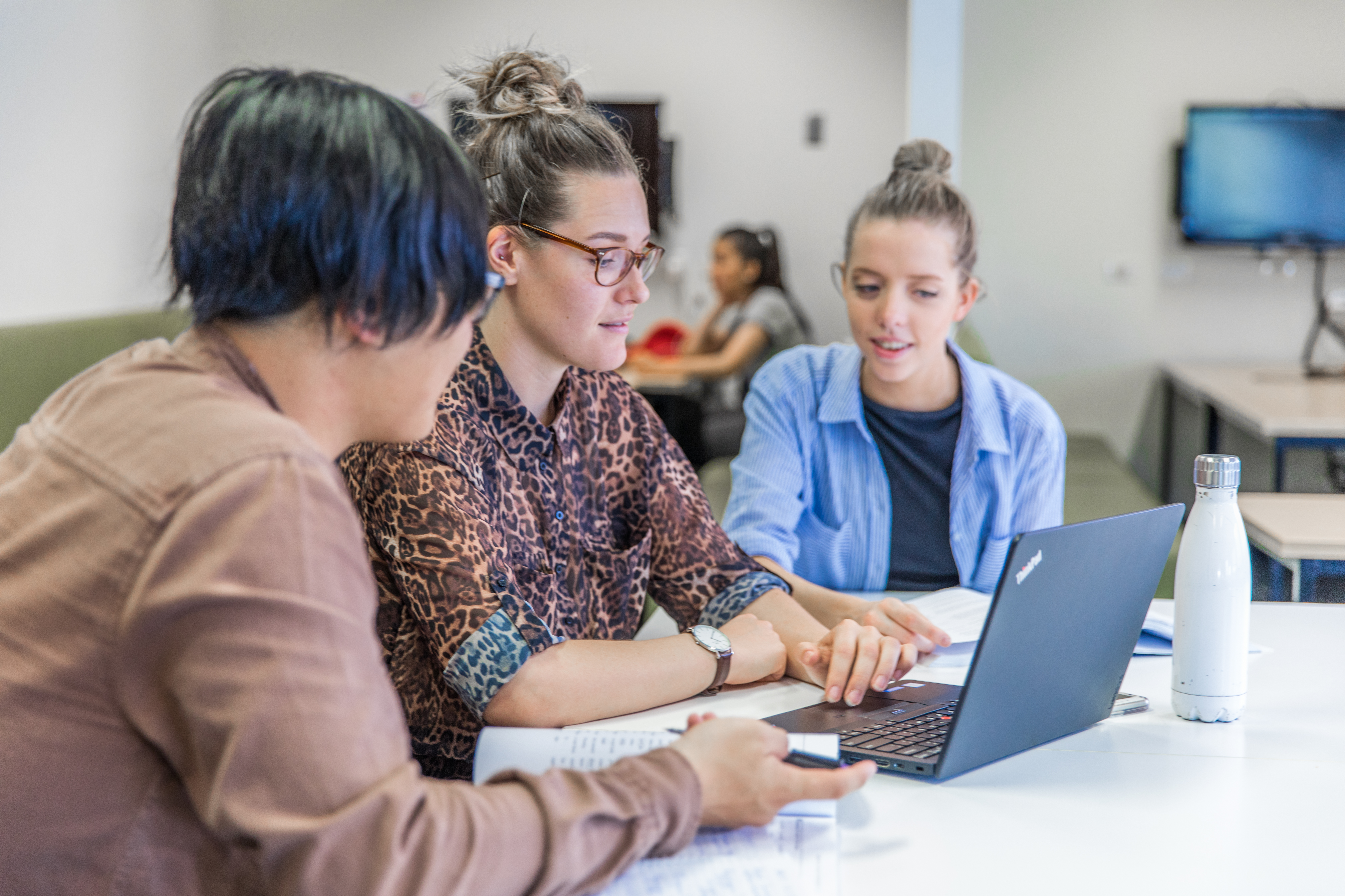 Three students studying on a laptop for a group project