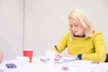 female business course student wearing yellow taking notes in the classroom