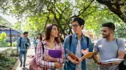 Young university students walking outdoors on campus and engaging in conversation.