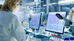 Female biomedical scientist at work in a laboratory analysing samples and DNA structures.