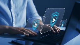 A businesswoman types on a laptop as security locks pop up around her - indicating that she is being protected from cyber attacks and her data is safe.