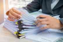 Hands young female business managers checking and arranging stack of unfinished documents reports papers for result graph marketing, startup project for plan job succes in Busy office with flare light