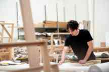 Carpentry student with a black t shirt and brown hair at work in a workshop.