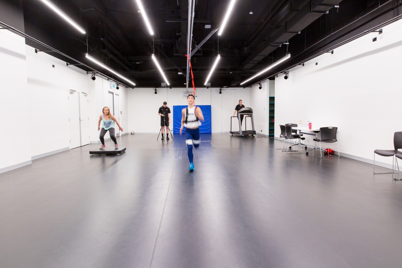 Long shot of three students performing different physical tasks and one student recording them with a camera