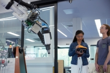 Male and female student in Protolab standing next to Kuka robotic arm